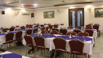 Sala de conferências com várias mesas e cadeiras, dispostas em fileiras.