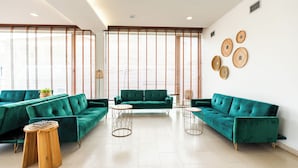 A modern living room with two green sofas, a wooden coffee table, and a round side table. - Hotel Evenia Monte Real (Leiria)