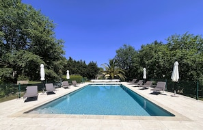 A rectangular swimming pool with lounge chairs and umbrellas, surrounded by trees and a clear blue sky. - La Résidence du Moulin (Tourrettes-sur-Loup)
