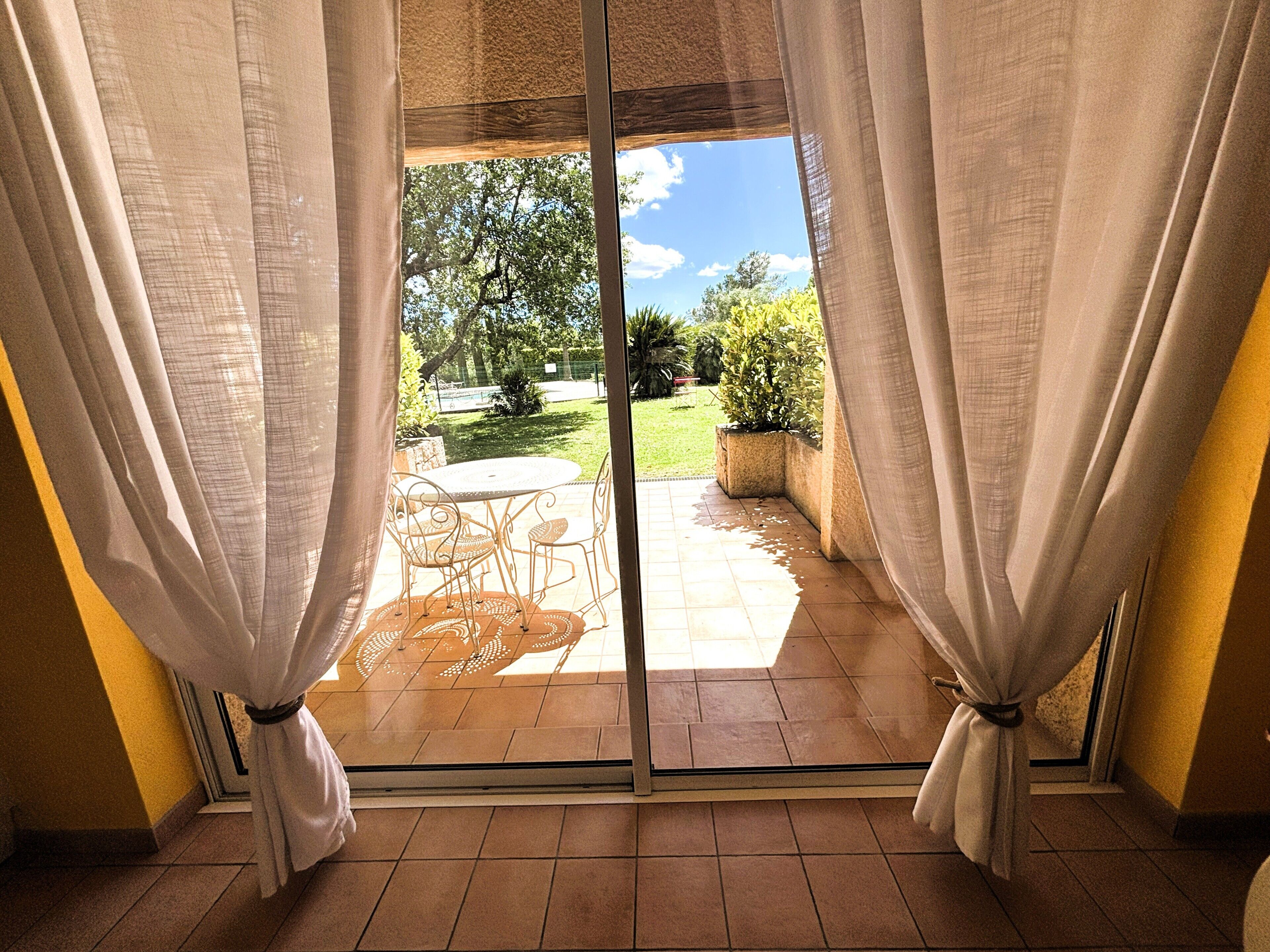 Una habitación con puerta corrediza de vidrio que da a un patio exterior con mesa y sillas.