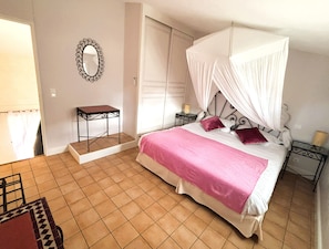 A bedroom with a bed, a nightstand, a mirror, and a chair.