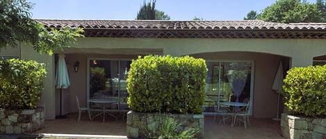 A house with a patio, a glass door entrance, and a stone wall.