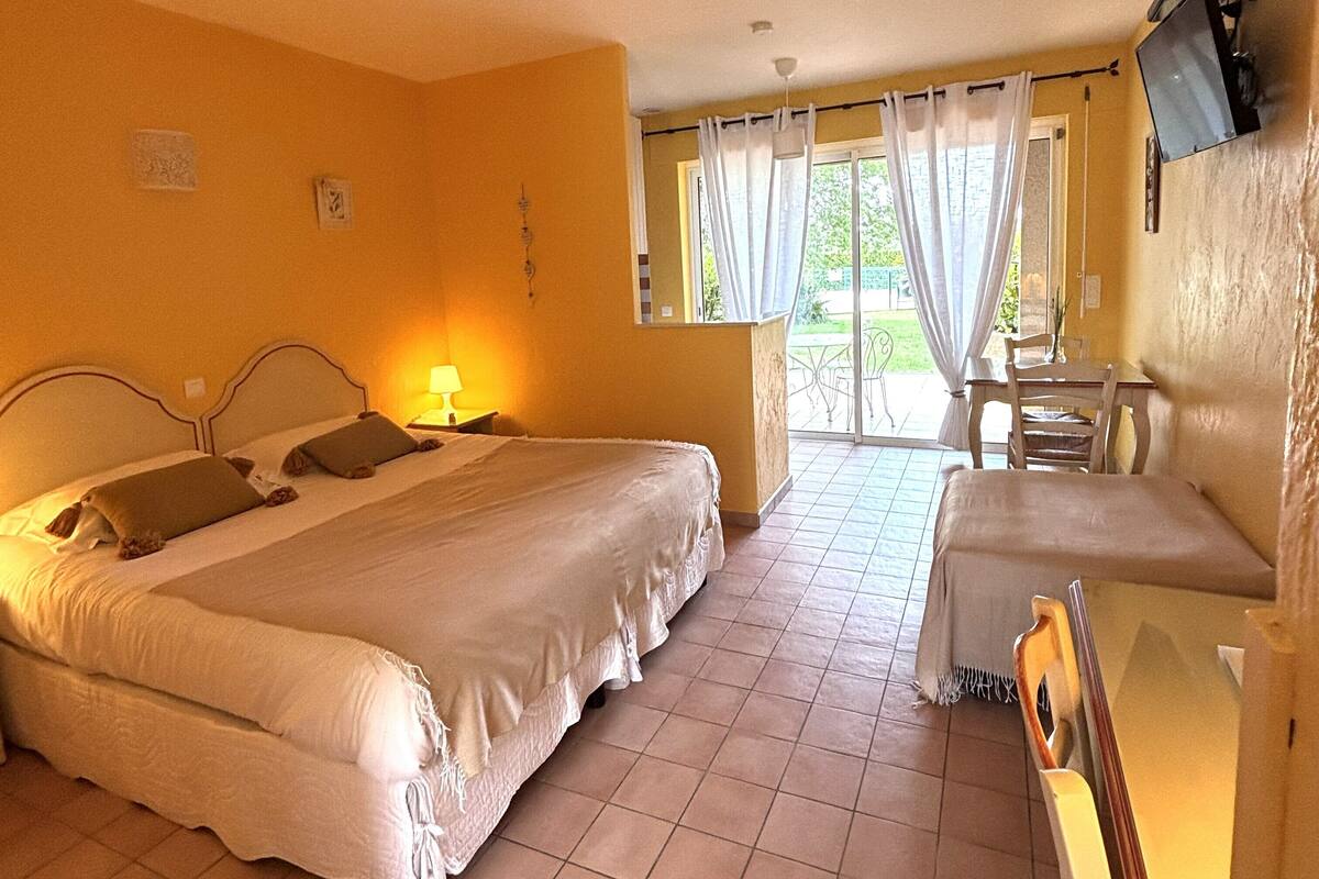 A hotel room with a bed, a desk, a chair, and a television.