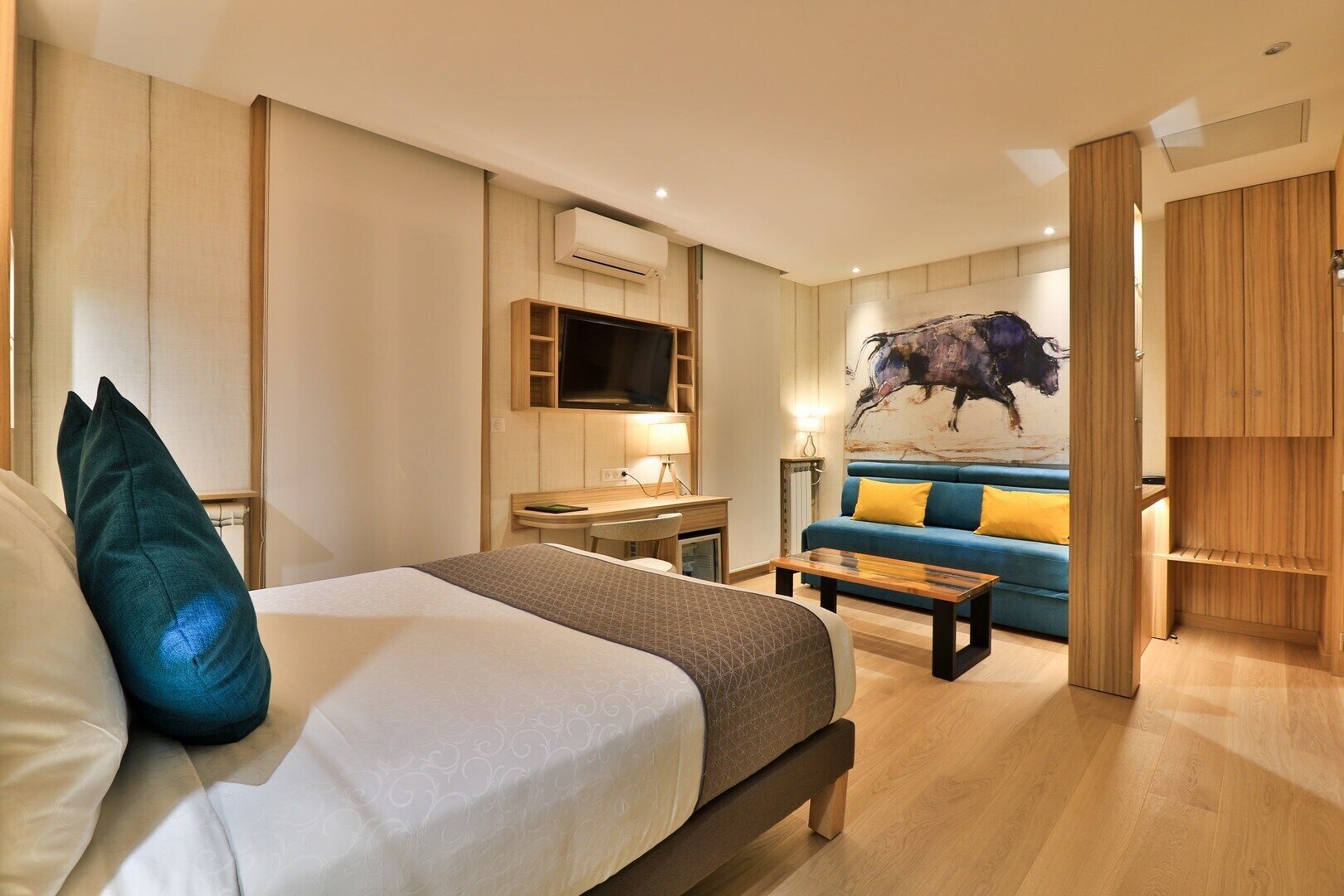 A hotel room with a bed, a desk, a sofa, and a TV.