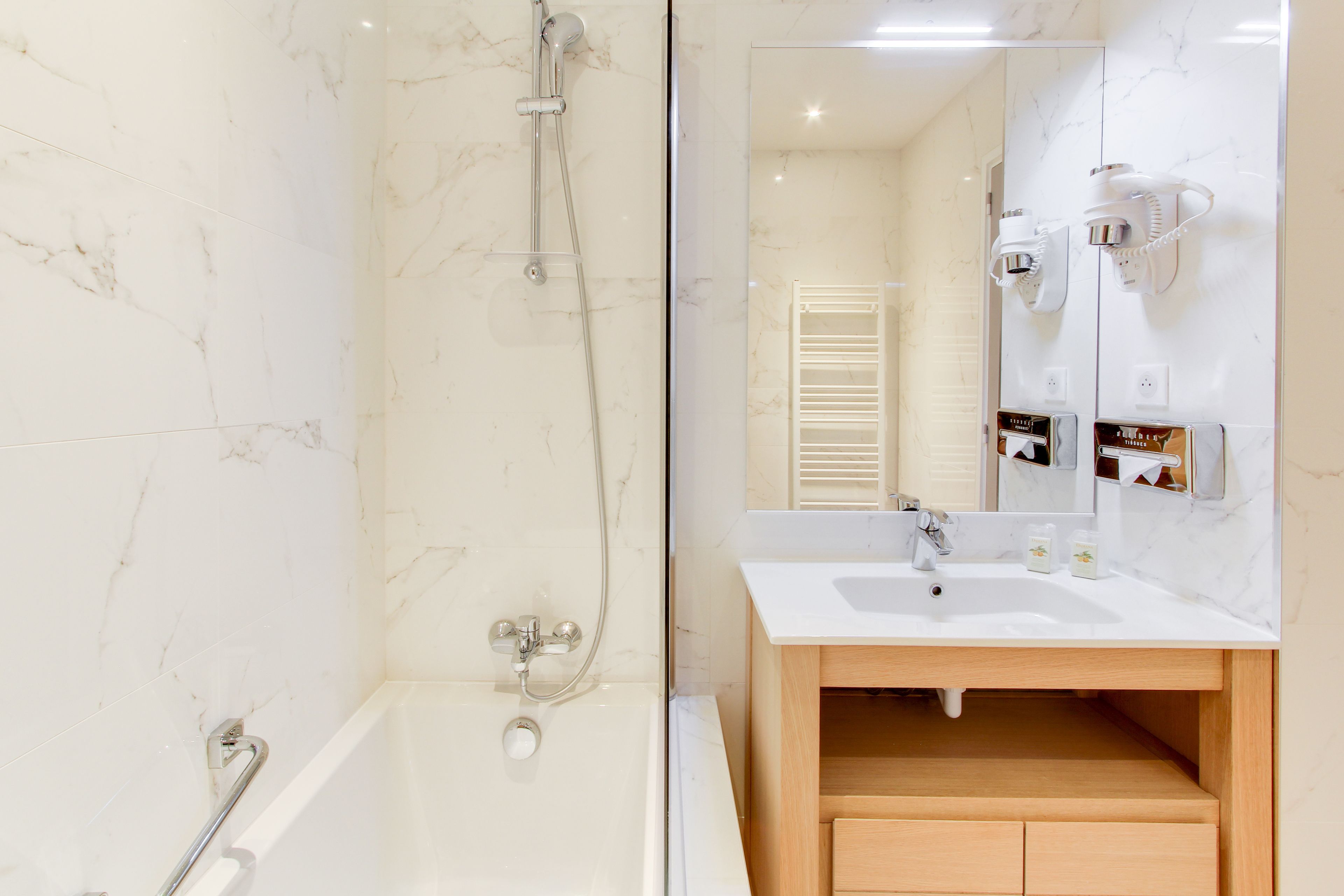 A modern bathroom with a glass-enclosed shower, a white sink with a wooden vanity, and a mirror with a towel rack.