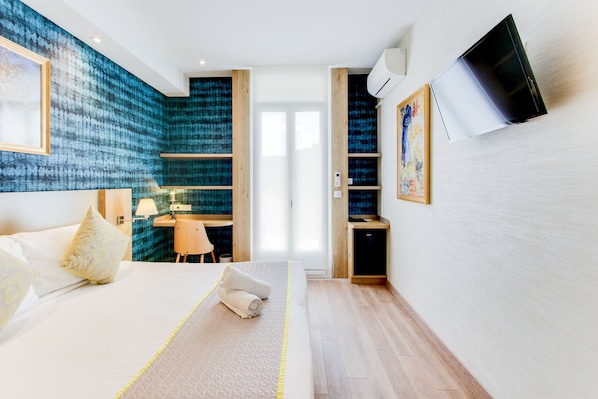 Una habitación de hotel moderna con una cama grande, un escritorio y un televisor montado en la pared.