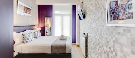 Um quarto moderno com uma cama, uma mesinha de cabeceira, um aquecedor fixado na parede e uma obra de arte emoldurada.