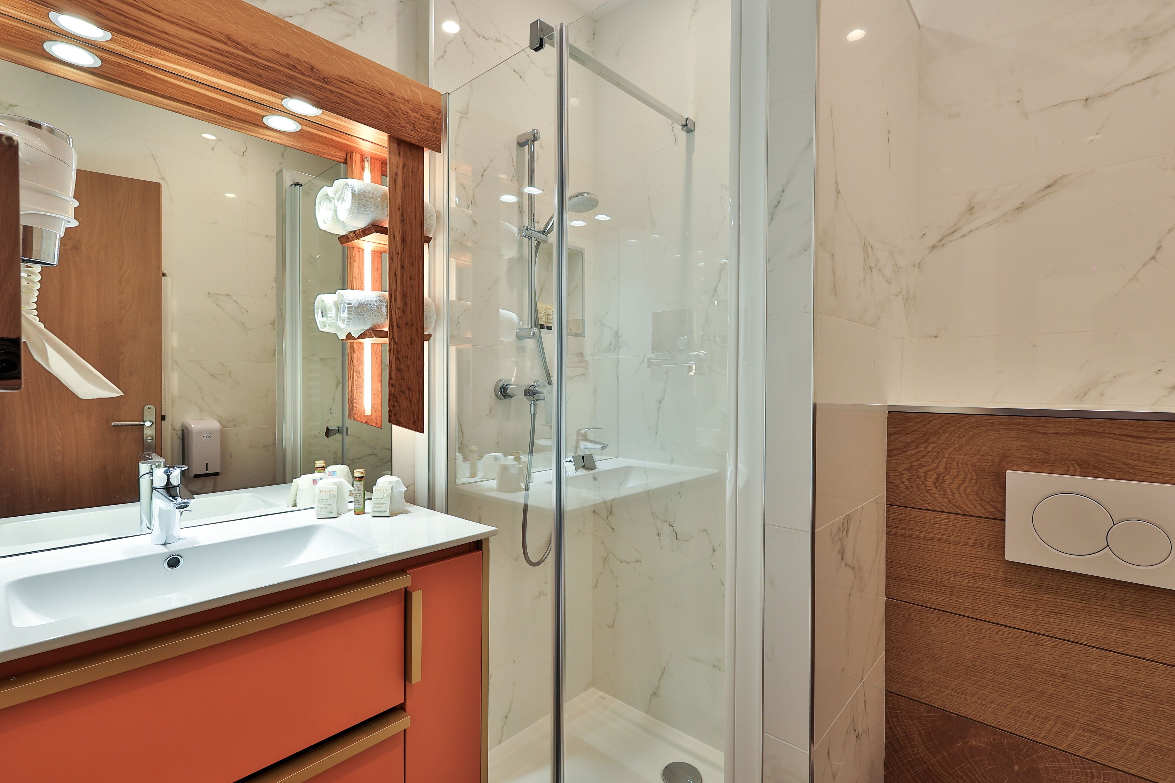 Un baño moderno con ducha envuelta en vidrio, un espejo grande y un tocador con lavamanos.