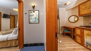Habitación de hotel con cama, escritorio, silla, espejo y una pequeña kitchenette.