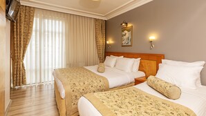 Habitación de hotel con dos camas, televisión, un cuadro y una ventana con cortinas.
