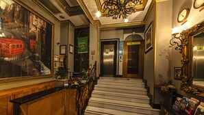 Una imponente escalera con acabado de mármol que conduce a un ascensor.