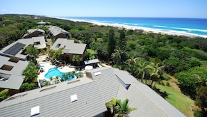 Um resort com piscina, vários edifícios e vista para a praia.