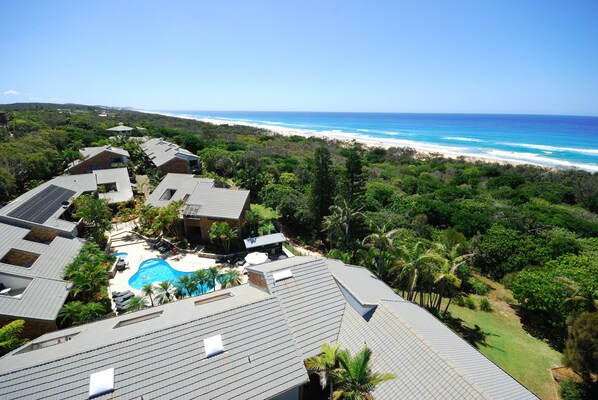 A resort with a swimming pool, multiple buildings, and a beach view.
