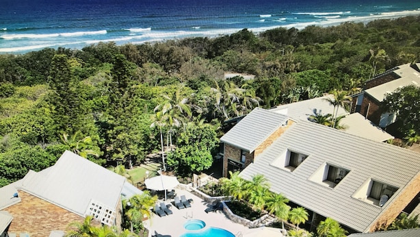 Um imóvel residencial com piscina, espreguiçadeiras e vista para o oceano.