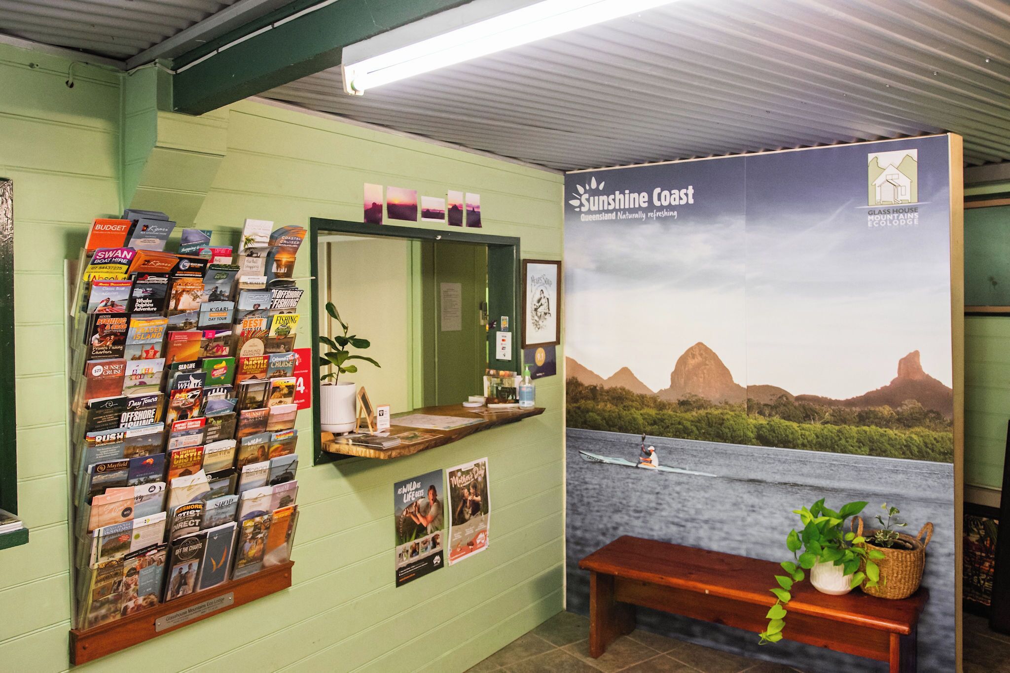 Un espace d’accueil comprenant un panneau d’information fixé au mur, un banc et une affiche représentant la région de Sunshine Coast.