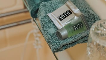 Een badkamer met een handdoekhouder, waarop een groene handdoek en een tube D-Lux badgel liggen.