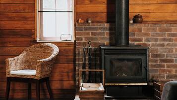 A rustic room with a brick fireplace, a wicker chair, and a wooden bench.
