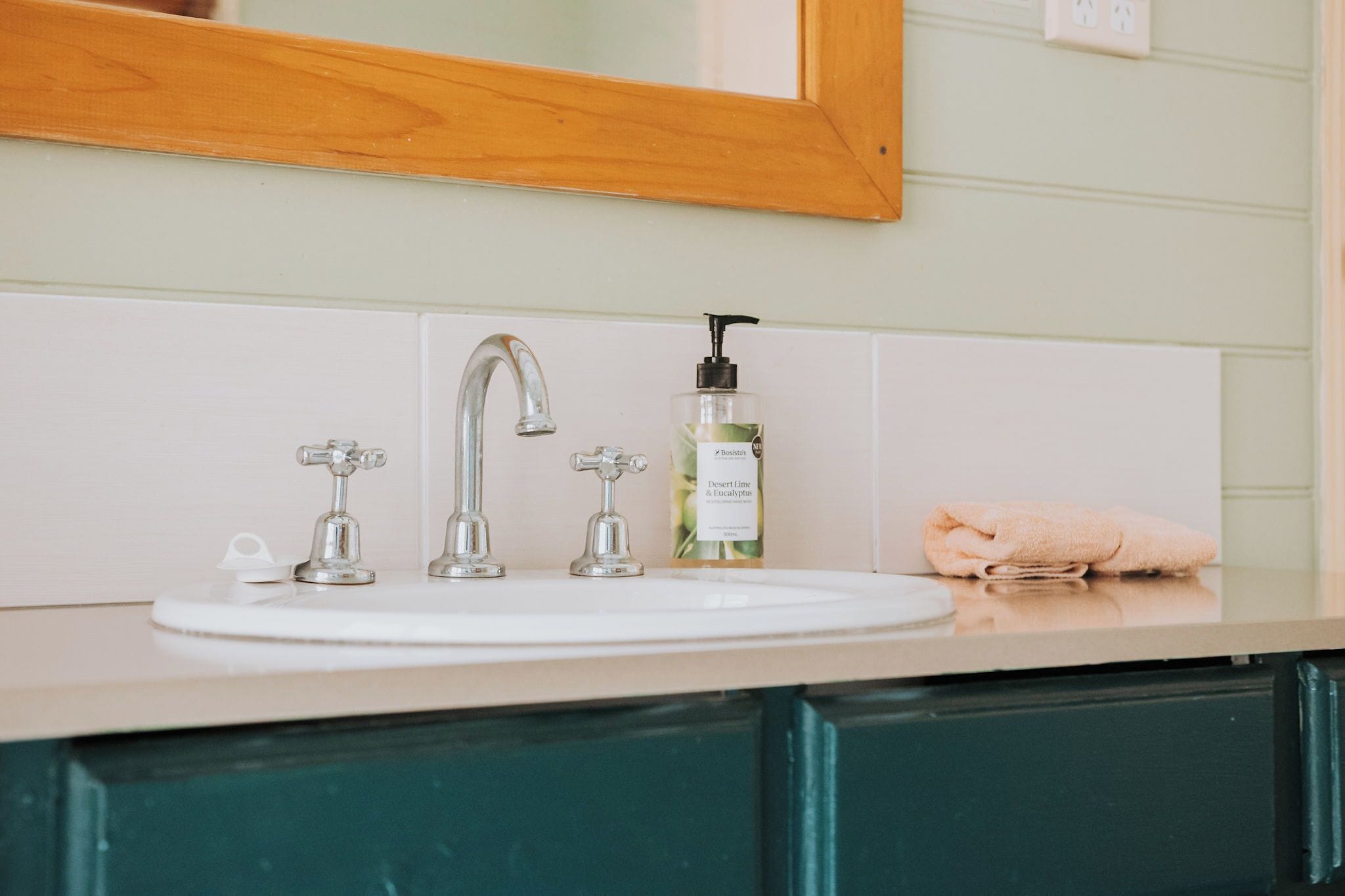 Ein Badezimmer mit einem weißen Waschbecken, einem Spiegel und einer Handseifenflasche.