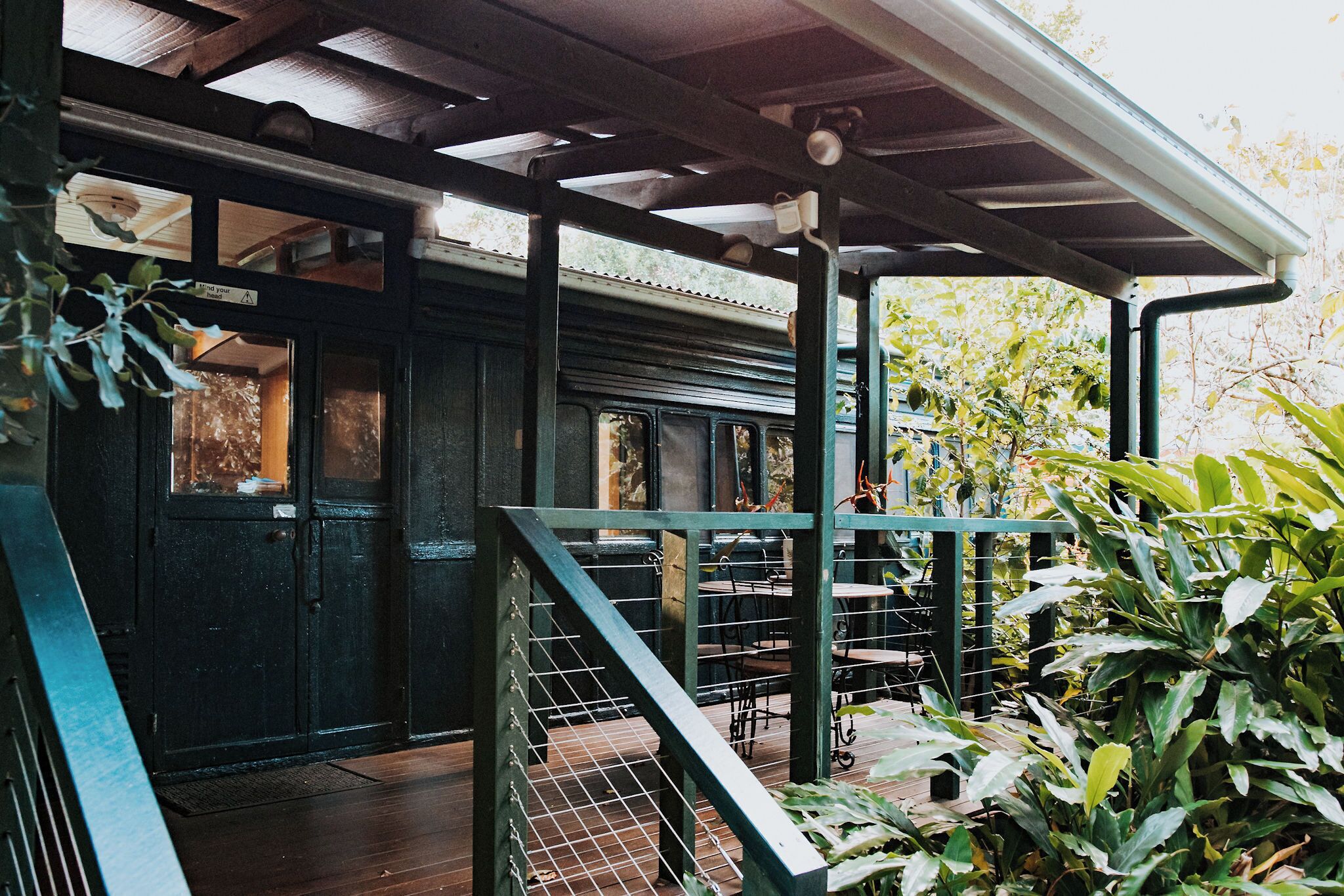 A covered outdoor area with a staircase, a door, and some greenery.