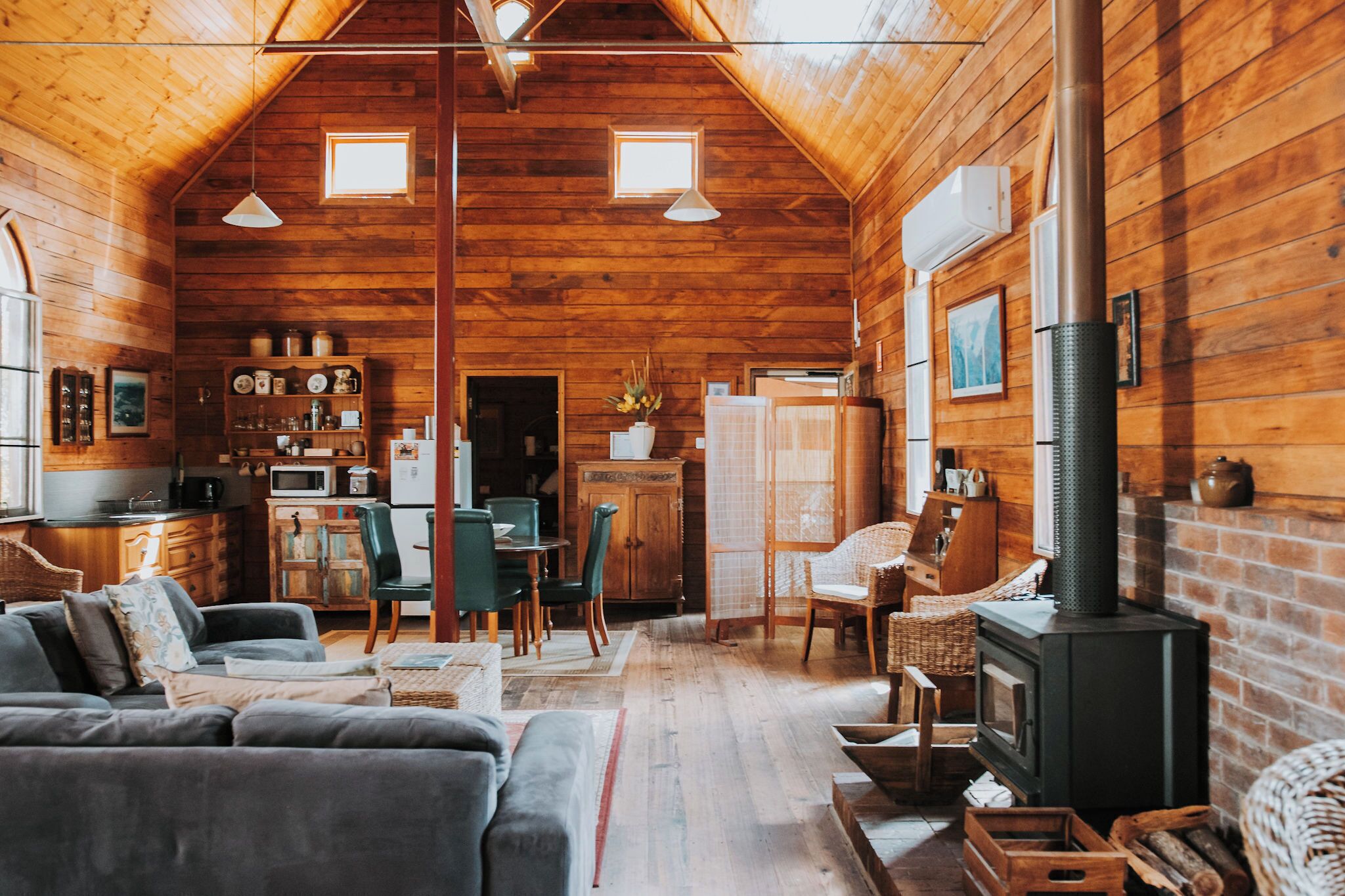 A cozy log cabin interior with a dining area, kitchen, and a fireplace.