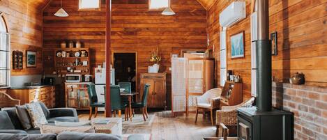 A cozy log cabin interior with a dining area, kitchen, and a fireplace.