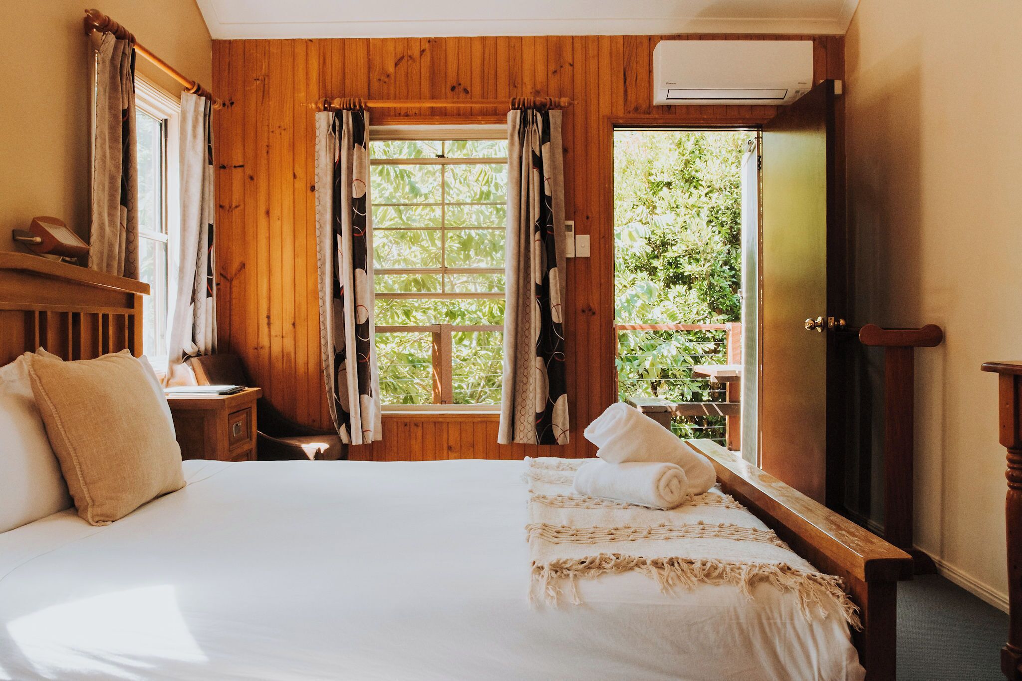 A wooden room with a bed, a window, and an air conditioning unit.