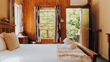 A wooden room with a bed, a window, and an air conditioning unit.