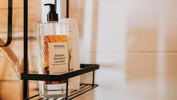 Un estante de baño con una botella de Bosistos Australian Native crema corporal y un dispensador con bomba.