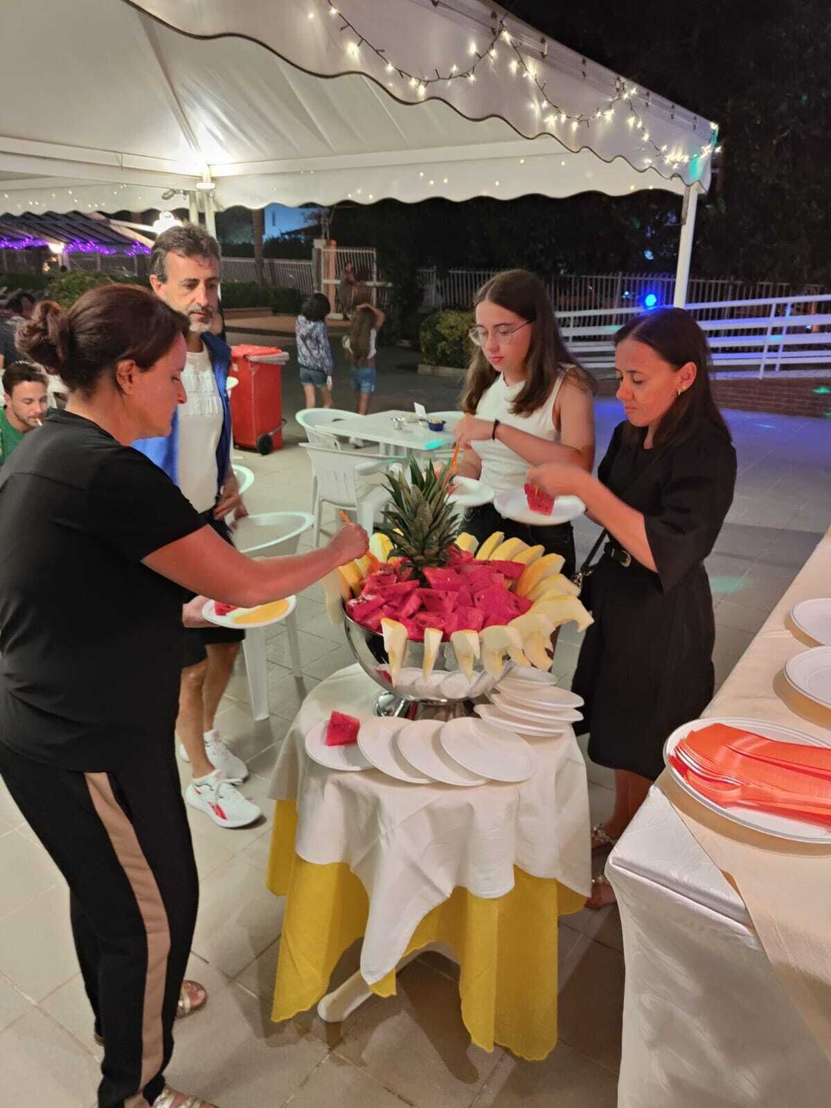 A buffet setup with a variety of fruits and a white tablecloth.