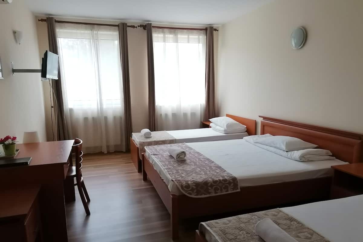 A hotel room with two beds, a desk, and a chair.