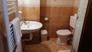 Une petite salle de bain avec un lavabo blanc, des toilettes et un porte-serviettes.