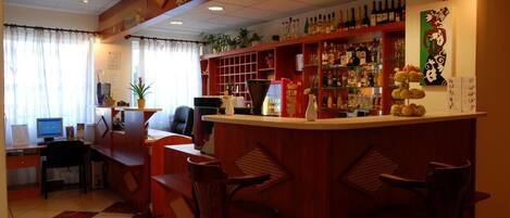A bar area with a counter, seating, and shelves stocked with bottles.
