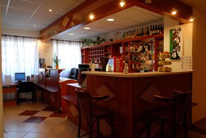 A bar area with a counter, seating, and shelves stocked with bottles. - Hotel Ferihegy (Budapest)