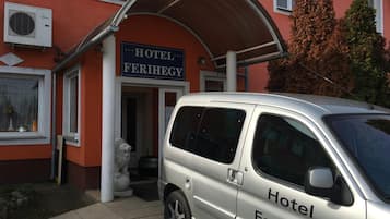 Una furgoneta plateada estacionada frente a un edificio con un letrero que dice 'Hotel Ferihegy'.