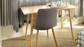 A room with a wooden table, a grey chair, a coffee maker, and a kettle. - Bavaria Boutique Hotel (Auckland)