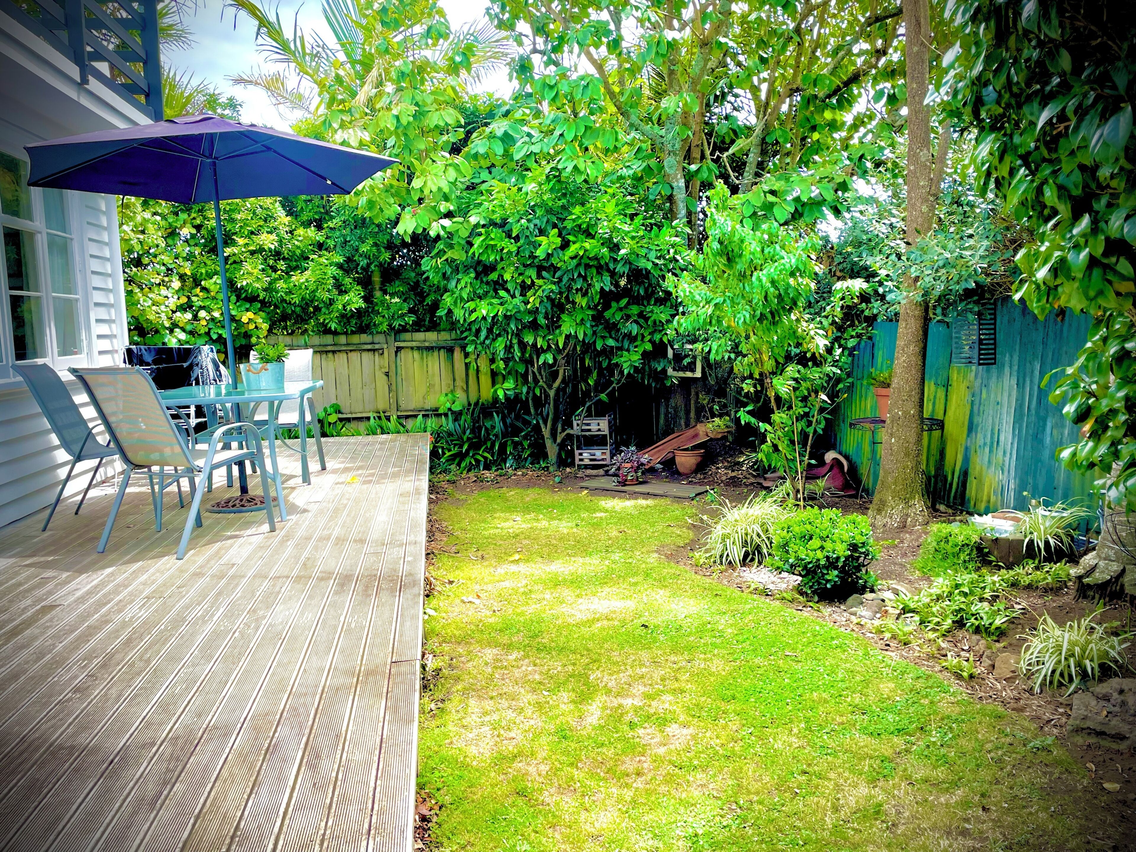 A backyard with a patio, chairs, a table, and a wooden fence.
