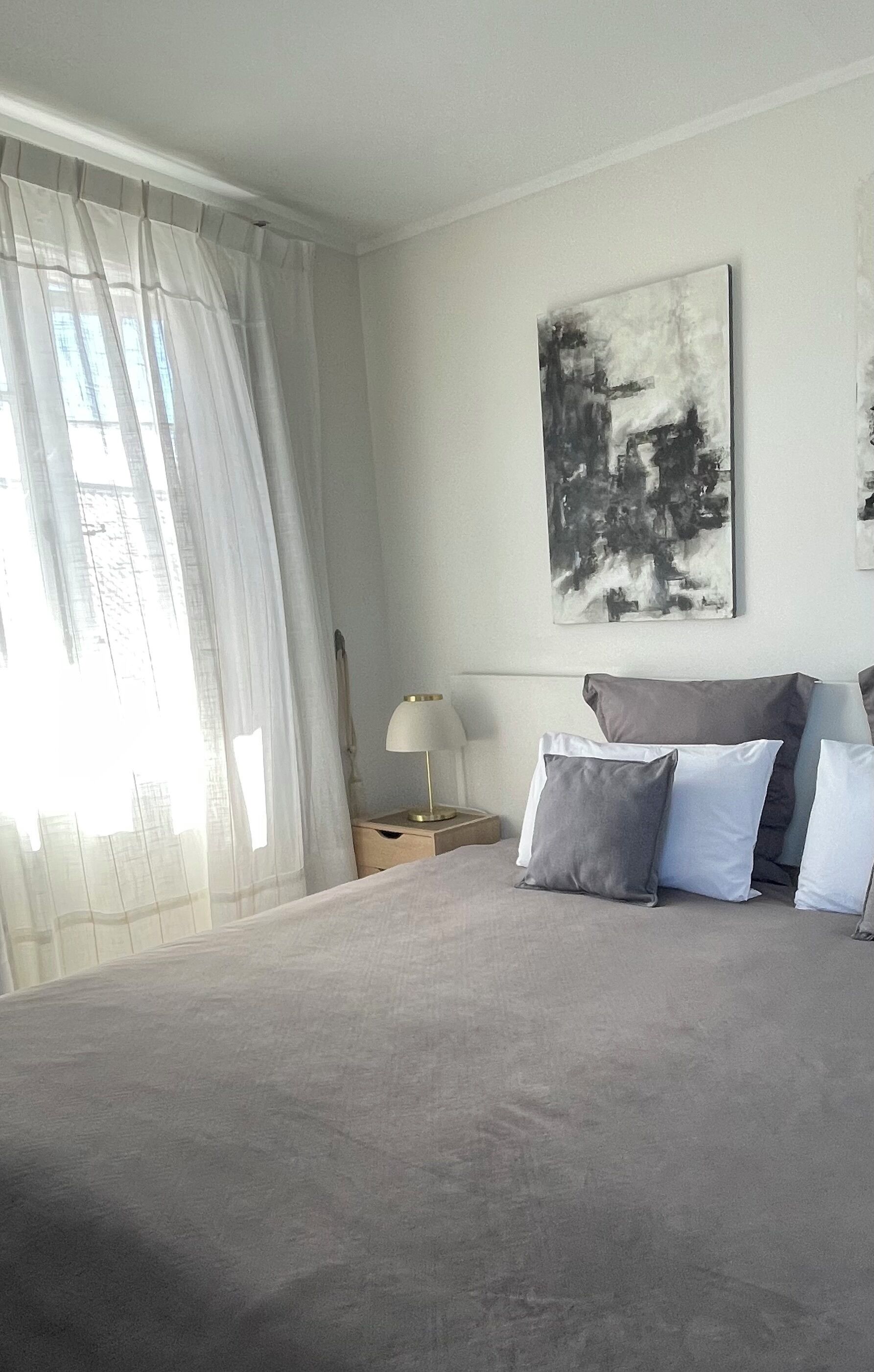 Ein Schlafzimmer mit einem großen Bett, einem Nachttisch mit Lampe und einem Bild an der Wand.