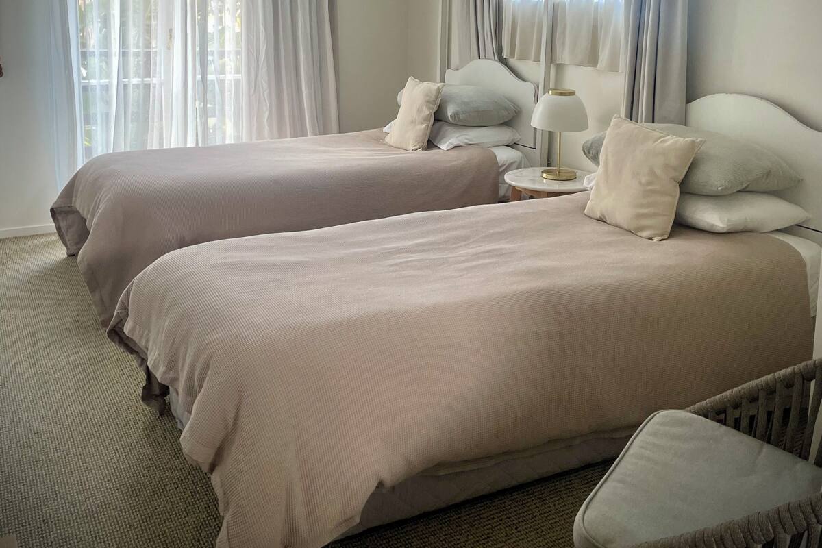 Habitación de hotel con dos camas, una mesita redonda y una silla.
