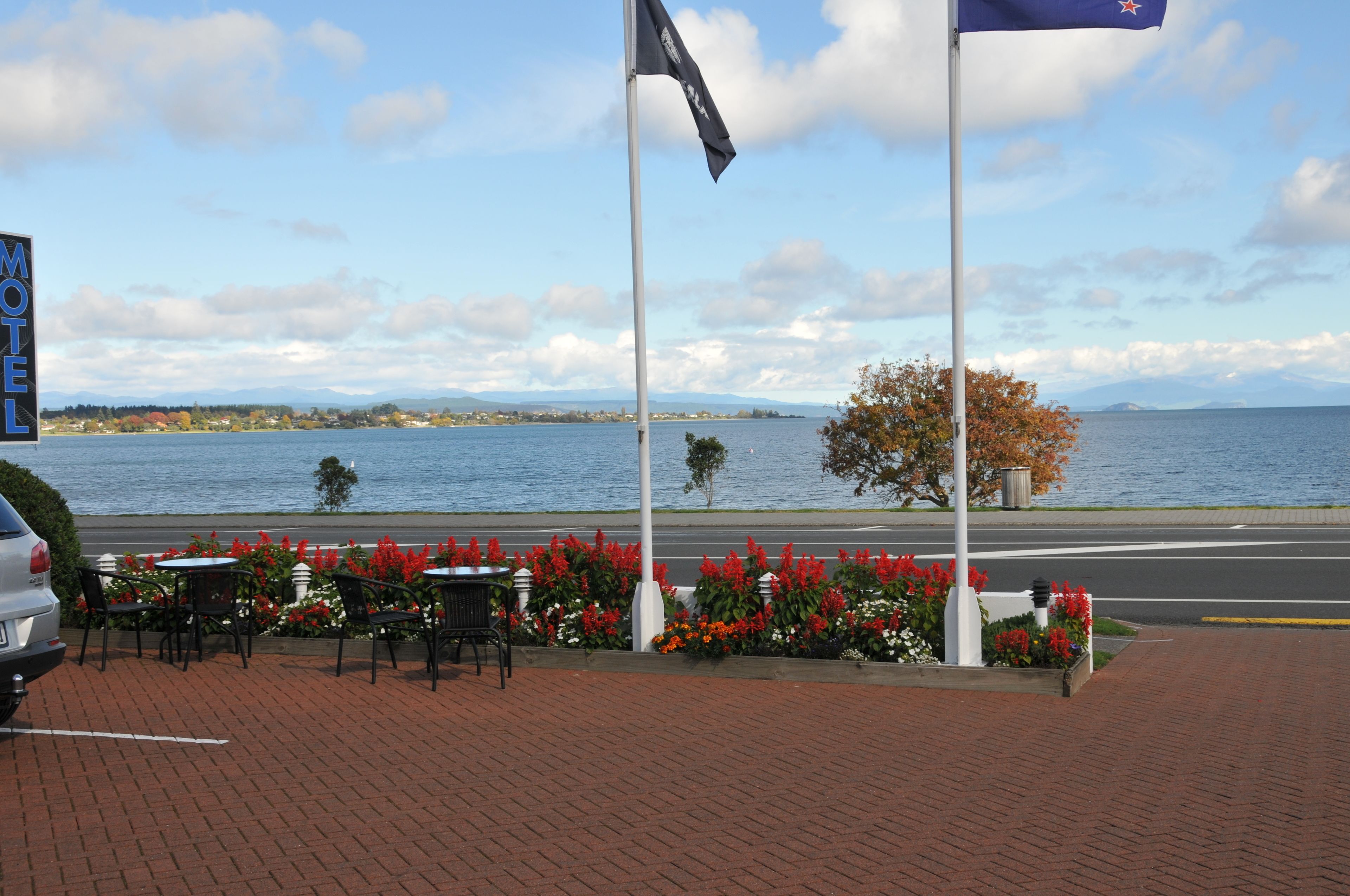 A waterfront patio with outdoor seating, a flagpole, and a sign for a motel.