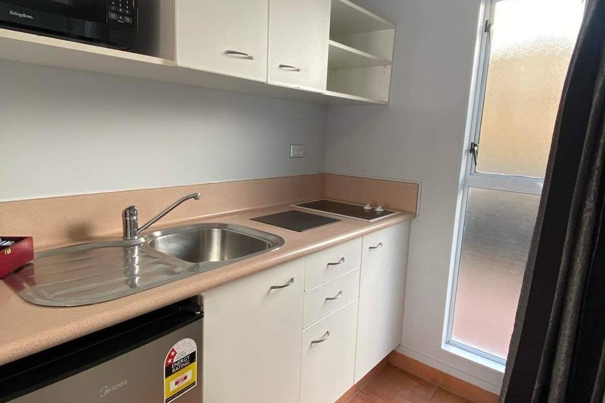A compact kitchen with a microwave, sink, and cabinets.