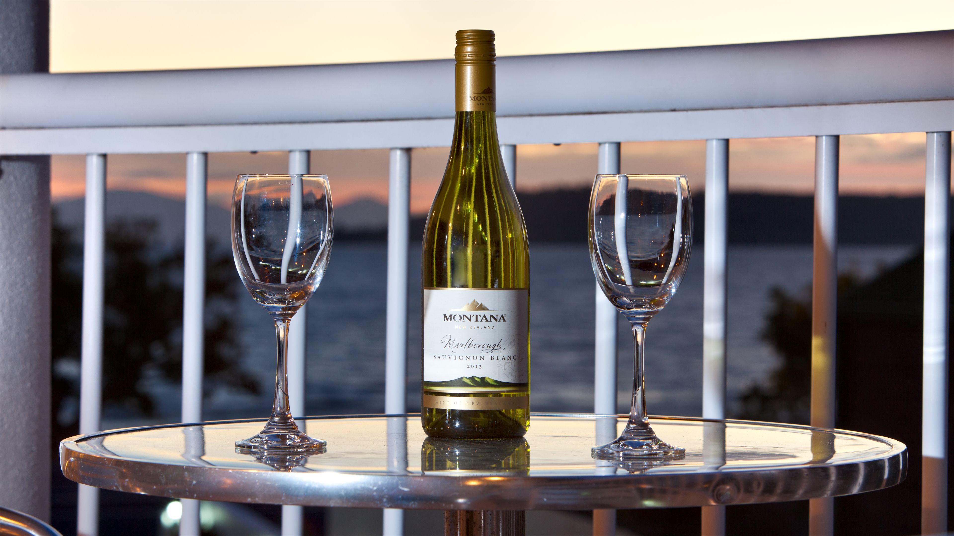 A bottle of Montana Sauvignon Blanc 2013 on a table with two empty wine glasses.