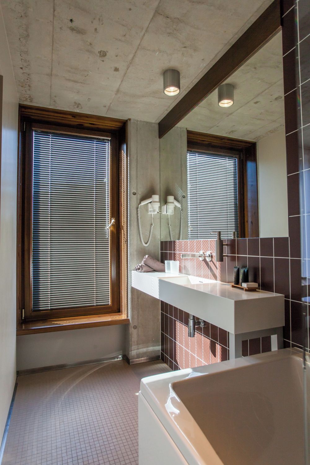 A modern bathroom with a large bathtub, a white sink, and a mirror.