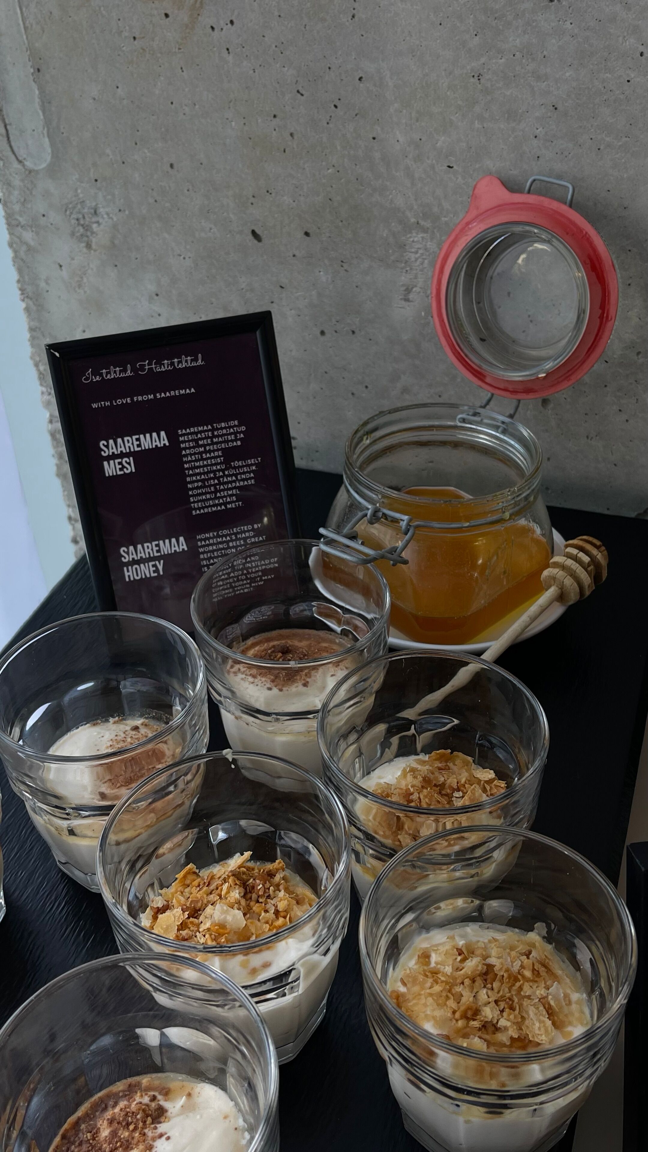 Una mesa con diferentes alimentos, incluyendo tarros de miel, tazones de cereales y una pizarra con el menú.