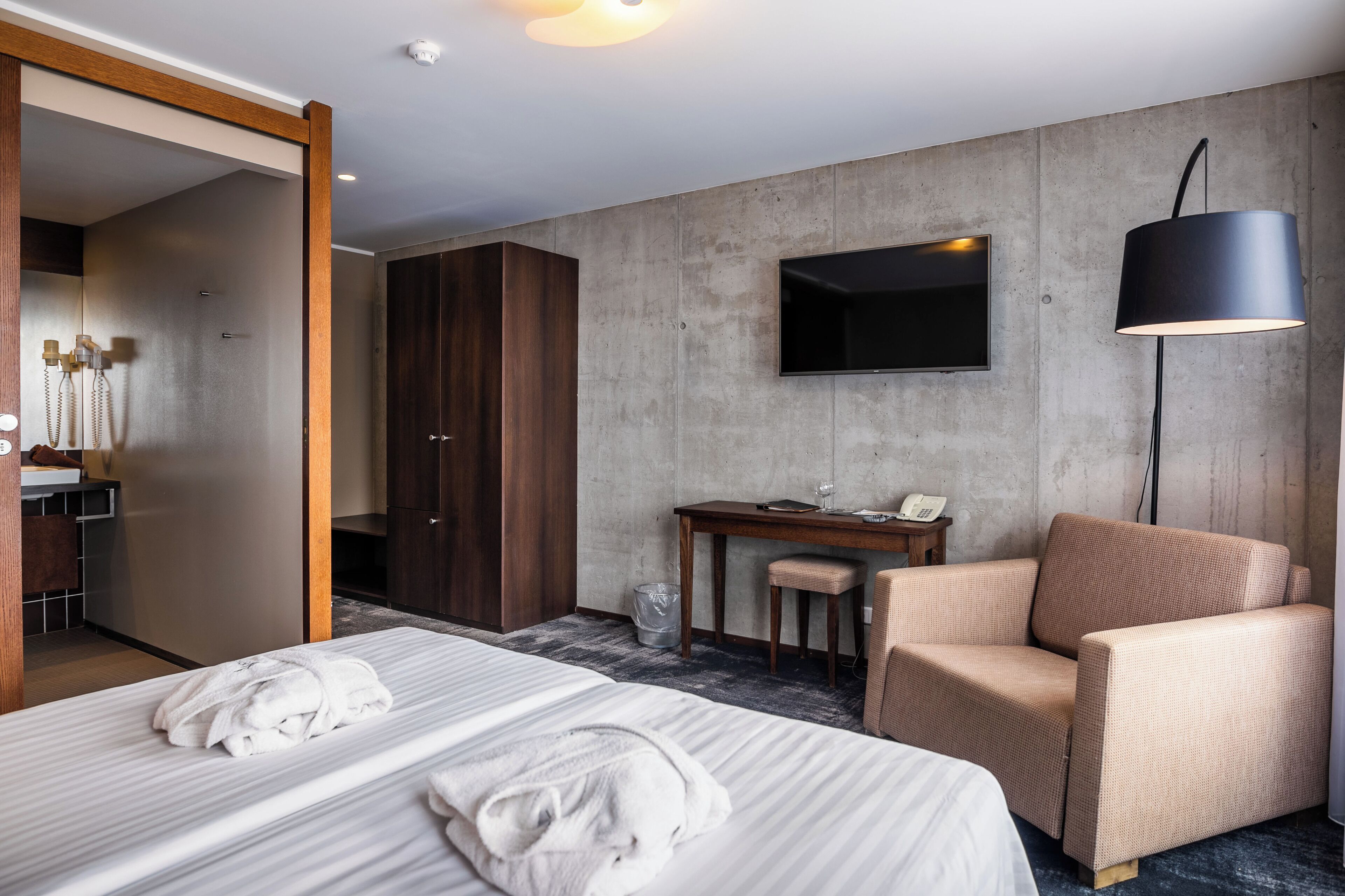 Habitación de hotel con dos camas, un escritorio, una silla, un televisor y un armario.