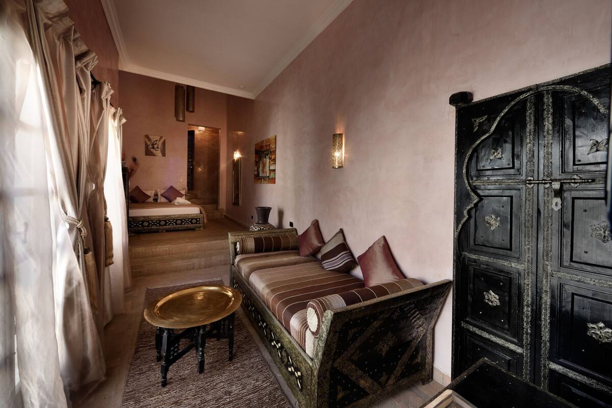 A traditional Moroccan room with a sofa, a small table, and a large wooden cabinet.