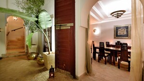 A dining area with a wooden table and chairs, a chandelier, and a framed picture on the wall. - Riad Les Ammonites (Marrakech)