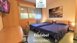 A room with two beds, a desk, and a TV. - Ethic Etapes Dijon (Dijon)