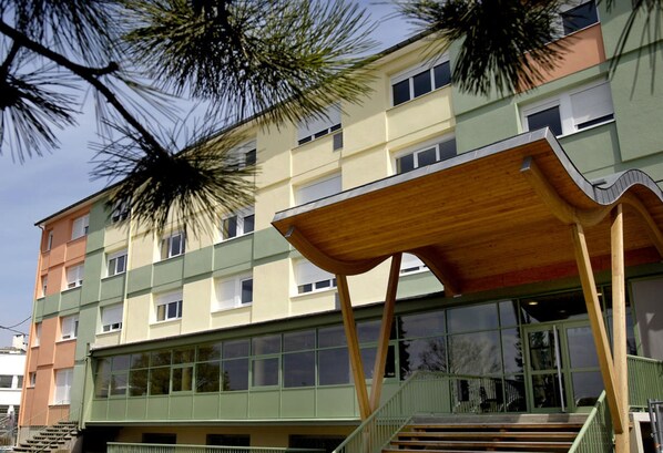 A multi-story building with a unique wooden structure on the ground floor, large windows, and a staircase leading to the entrance. - Ethic Etapes Dijon (Dijon)