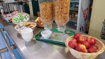 Um buffet de café da manhã com cereais, iogurte e maçãs.