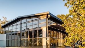 A modern glass conservatory with a metal roof, surrounded by trees. - Premier Resort The Moorings, Knysna (Knysna)